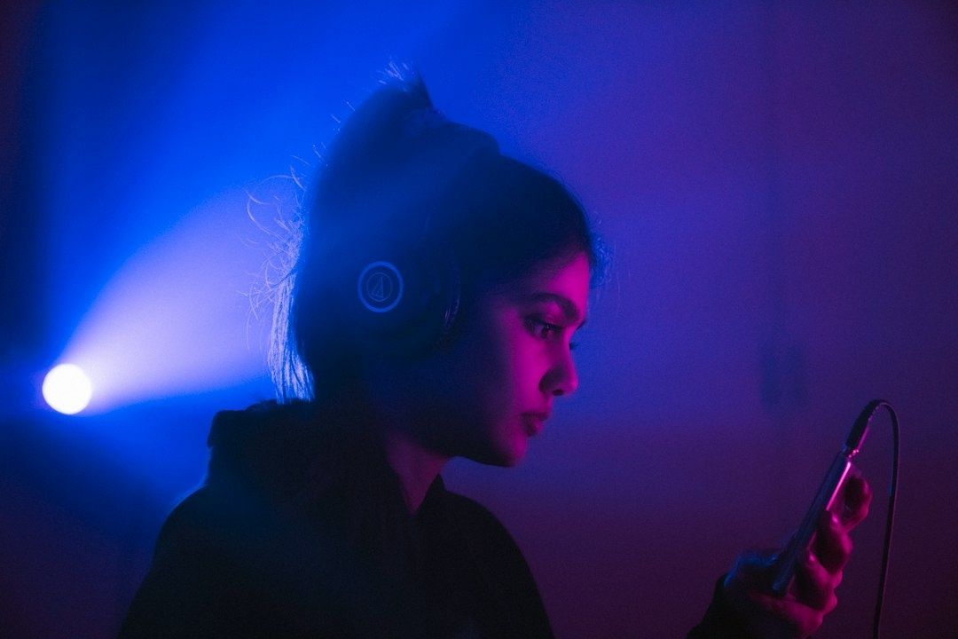 Henkilö kuuntelee musiikkia kuulokkeilla ja käyttää älypuhelinta