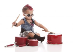 Adorable toddler dressed as a rock star with a hot pink Mohawk and drumming on some pots and pans. Isolated on white.